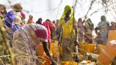 Group of African women and children with jugs of fresh water
