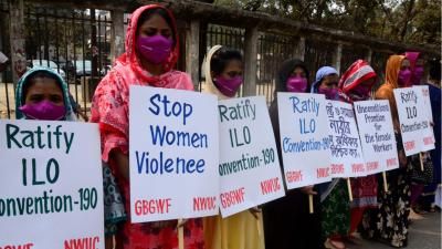 Group of women from the International Labour Organisation holding up hand written signs protesting against violence and harassment in the work place 