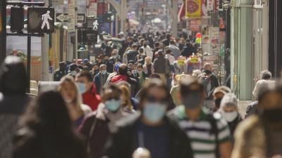 Very busy crowd in public space where several people are wearing facemasks