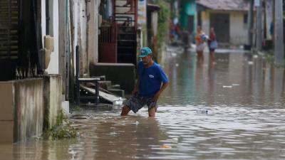 Man stood on flooded road as water comes up to his knees