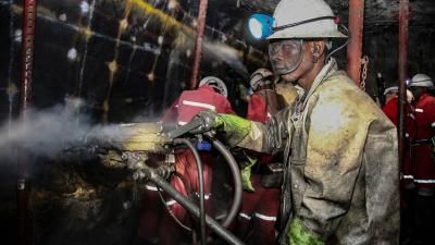 A group of miners working, their uniforms are dirty. They can be seen operating heavy machinery.