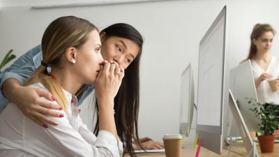 Two women looking at a computer, one comforts the other as the other woman looks distressed