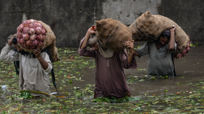 Three people wading through a flooded streey in Lahore, Pakistan.