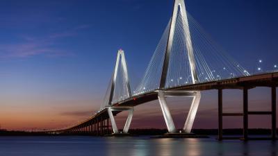 A modern bridge with a colourful sky in the background.