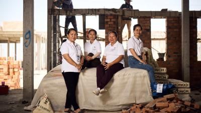 A group of women in uniform sitting on a pile of cement bags in Cambodia.
