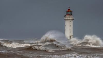 A lighthouse being hit by a wave.