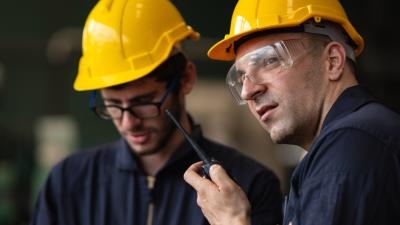 two construction workers communicating on a walkie talkie