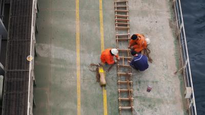 ariel view of two seafarers fixing laddering on ship