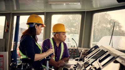Two people wearing PPE on the bridge of a ship.