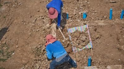 two construction workers shovel rubble