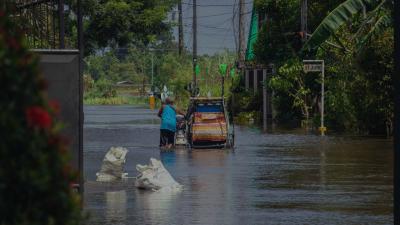 Man pushing his pedicab as he walks through a flooded street