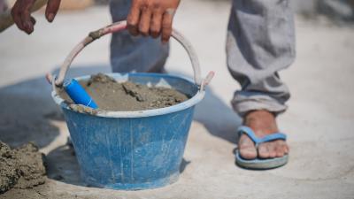 construction worker holds bucket of cement 