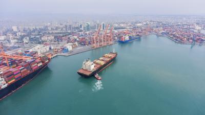 Aerial view of Cargo Container Ship approaching port with tugboat
