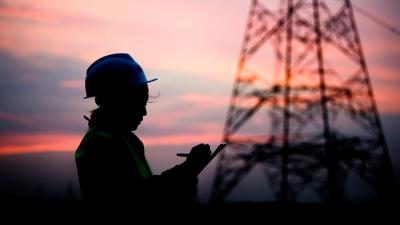 A woman wearing PPE standing in front of a pylon.
