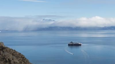 Small cruise boat sits against backdrop of mountains in Greenland