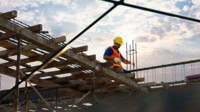 male engineer stand on stop of construction site wearing yellow hard hat