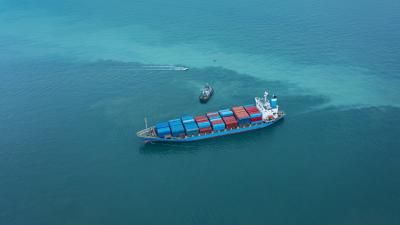 Aerial top view tug boat pulling container cargo ship to loading dock on the sea for business logistics, import export shipping or freight transportation.