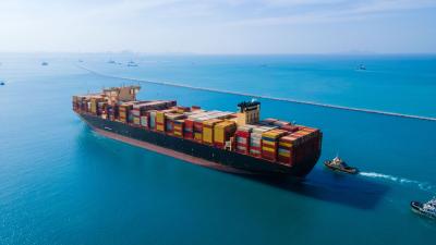 Aerial view of large container ship loaded with colourful shipping containers on blue ocean waters