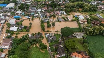 Aerial view of a flooded residential area with muddy water surrounding houses and partially submerged streets.
