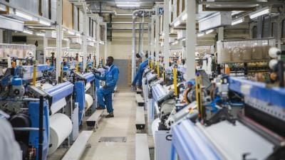 Engineers in blue uniforms in long production hall