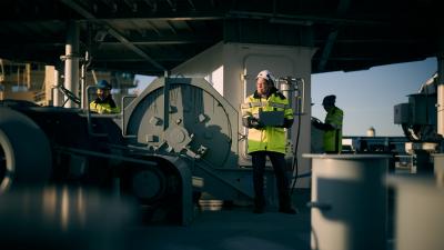 Ship workers in high-visibility safety gear on board boat