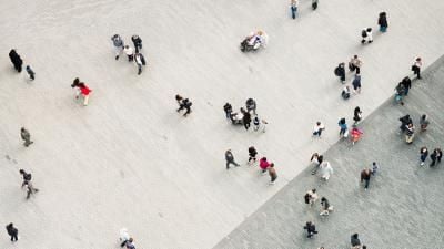 Aerial view of people scattered across a large stone plaza, seen from above as tiny figures moving about.