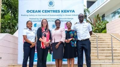Group of professionals standing in front of Ocean Centres Kenya banner at sustainability event.