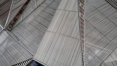 Modern architectural detail showing geometric pattern of metallic slats forming angular surfaces on a building facade.