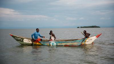 Fishermen in a colorful wooden boat on a lake, with small island visible in the distance.
