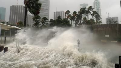 Storm surge with powerful waves crashing against a seawall in a coastal city during a hurricane.